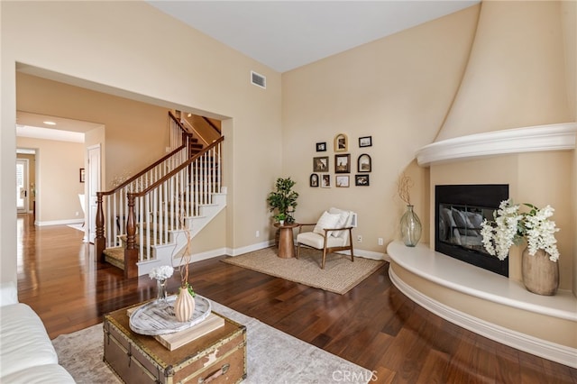 living room featuring a large fireplace, stairway, wood-type flooring, and baseboards