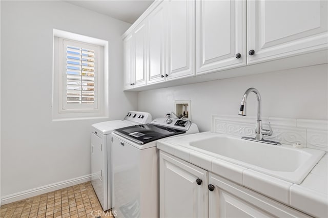 washroom with washing machine and clothes dryer, a sink, cabinet space, and baseboards