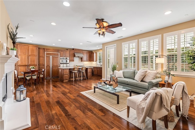 living room with dark wood finished floors, recessed lighting, a fireplace with raised hearth, visible vents, and a ceiling fan