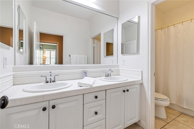 bathroom featuring double vanity, a sink, toilet, and tile patterned floors