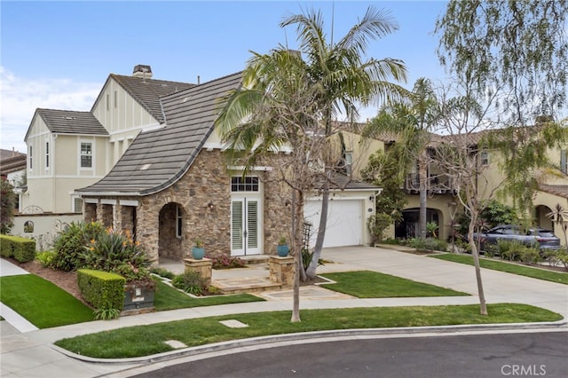 view of front of property featuring a tile roof, a chimney, concrete driveway, a garage, and stone siding