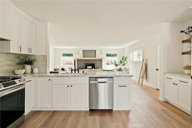 kitchen featuring a healthy amount of sunlight, appliances with stainless steel finishes, light wood-type flooring, and a peninsula