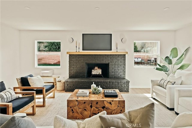 living area featuring a brick fireplace and wood finished floors