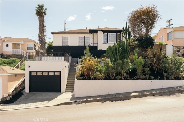 view of front of house featuring stairway, concrete driveway, and stucco siding