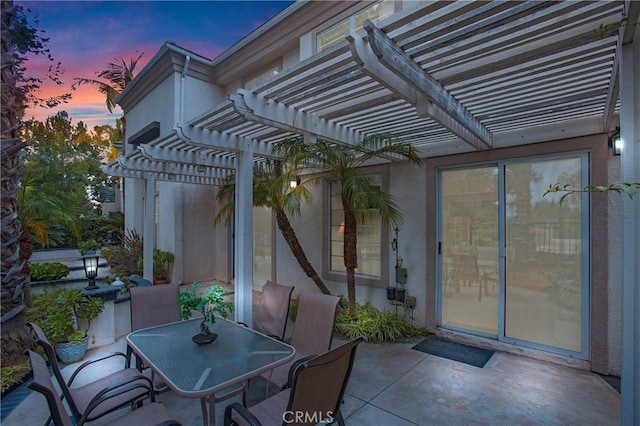 patio terrace at dusk with outdoor dining space and a pergola