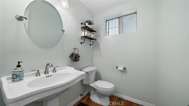 bathroom with baseboards, a sink, toilet, and wood finished floors