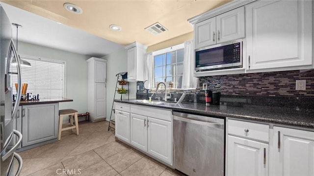 kitchen with appliances with stainless steel finishes, dark countertops, a sink, and visible vents