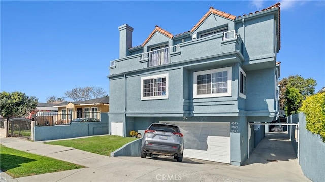 view of front of home featuring stucco siding, a gate, fence, a balcony, and a garage