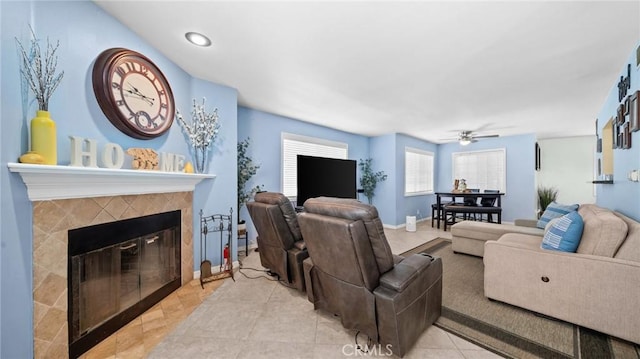 living room with light tile patterned floors, baseboards, a ceiling fan, and a tile fireplace