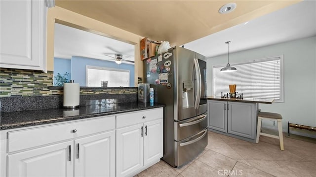 kitchen featuring light tile patterned floors, pendant lighting, white cabinetry, stainless steel refrigerator with ice dispenser, and backsplash