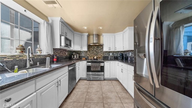 kitchen featuring light tile patterned floors, visible vents, stainless steel appliances, wall chimney range hood, and a sink