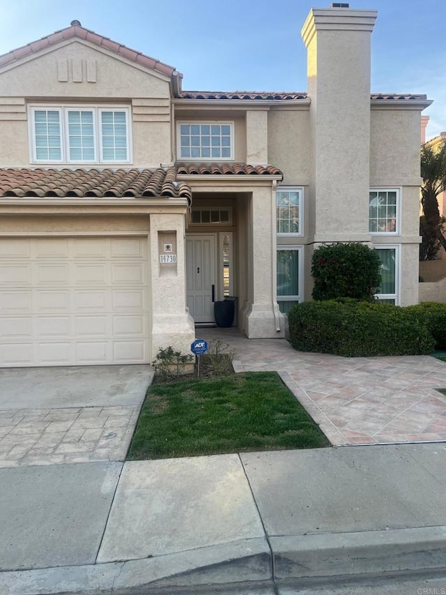 multi unit property with a chimney, stucco siding, driveway, and a tile roof