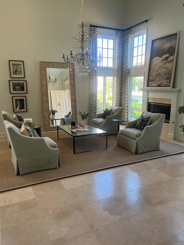 living room with a chandelier, a high ceiling, and a glass covered fireplace