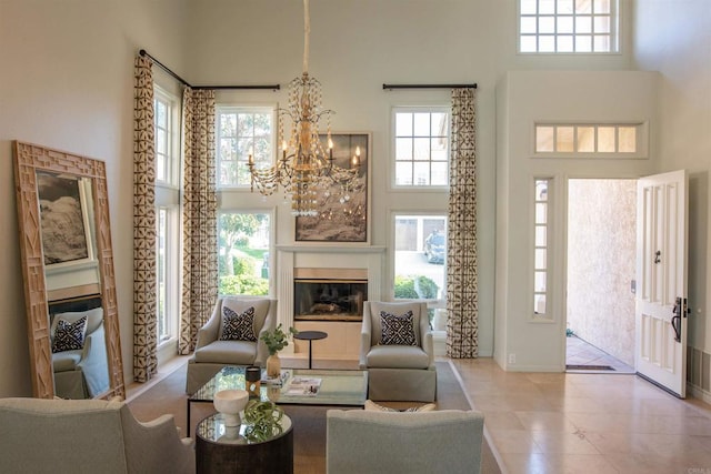 living area featuring a glass covered fireplace, a chandelier, and a towering ceiling