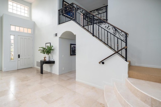foyer entrance featuring visible vents, arched walkways, a high ceiling, and baseboards