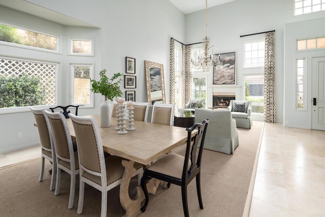 dining area with a notable chandelier, baseboards, and a towering ceiling
