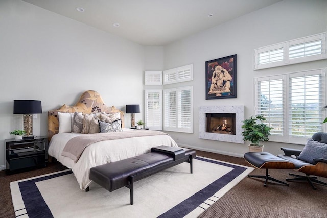 bedroom with baseboards, carpet floors, a high ceiling, and a fireplace
