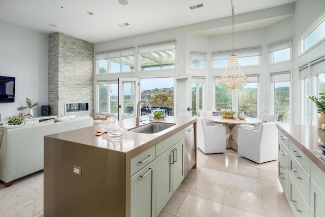 kitchen with a sink, stainless steel dishwasher, open floor plan, a fireplace, and a towering ceiling