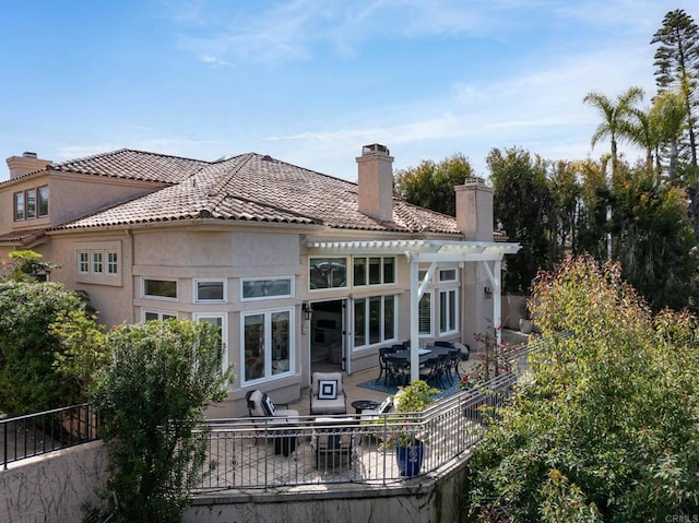 back of property with stucco siding, a pergola, a patio, fence, and a chimney
