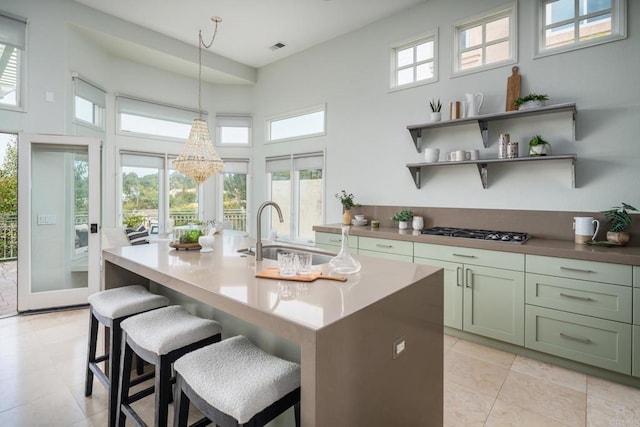 14730 Caminito Porta Delgada, Del Mar, CA 92014 - kitchen featuring a sink, stainless steel gas cooktop, a towering ceiling, an island with sink, and decorative light fixtures