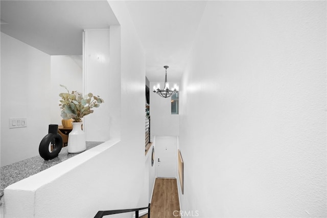 hallway featuring wood finished floors and a notable chandelier