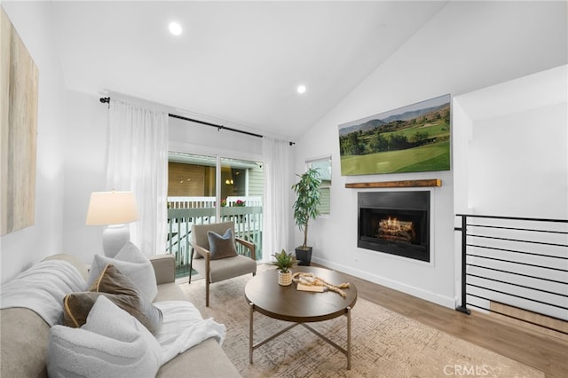 living room with vaulted ceiling, a lit fireplace, wood finished floors, and recessed lighting