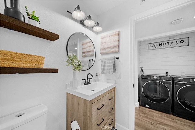 bathroom featuring toilet, washer and clothes dryer, wood finished floors, and vanity