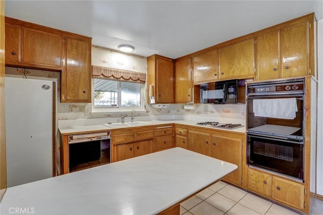 kitchen featuring brown cabinets, black appliances, a sink, light tile patterned flooring, and light countertops