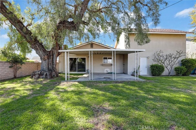 rear view of property with a yard, a patio area, stucco siding, and fence