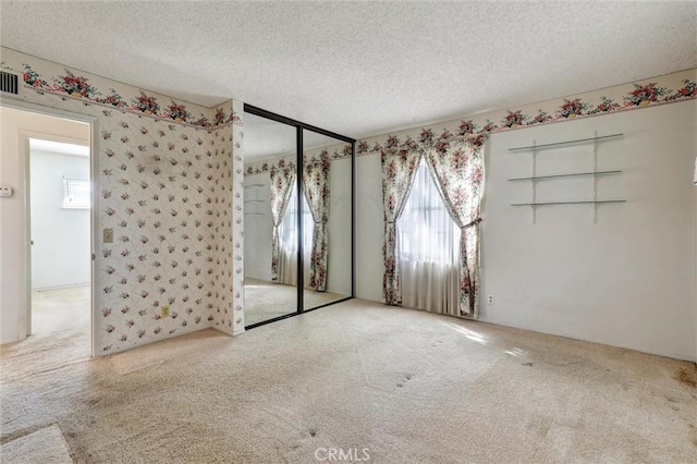 carpeted spare room with visible vents and a textured ceiling