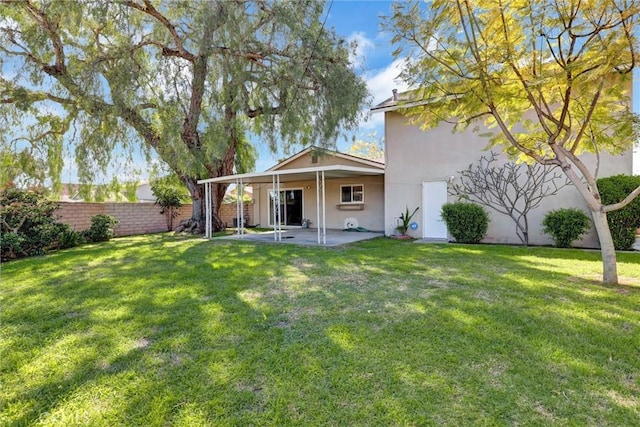 rear view of house featuring a patio area, stucco siding, a yard, and fence