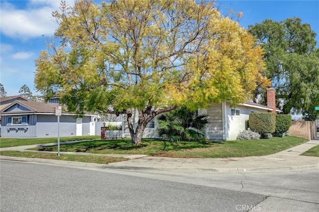 view of property hidden behind natural elements with a front lawn and fence