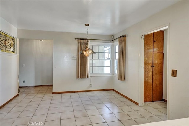 unfurnished dining area with light tile patterned floors, baseboards, and an inviting chandelier