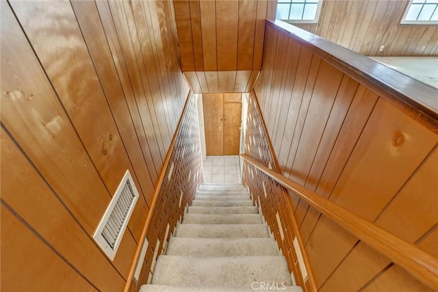 stairs featuring visible vents, a healthy amount of sunlight, and wood walls