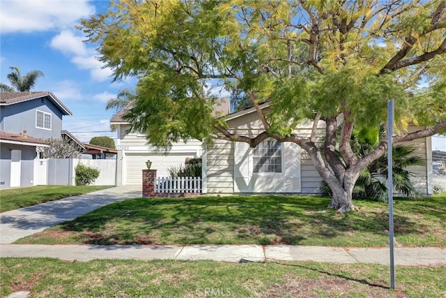 view of property hidden behind natural elements featuring a front lawn, fence, and driveway