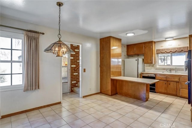 kitchen featuring a peninsula, freestanding refrigerator, light countertops, dishwasher, and brown cabinets