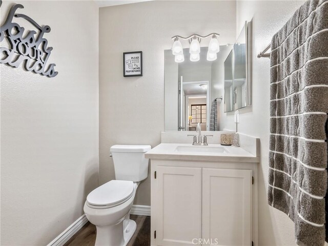 bathroom with vanity, wood finished floors, toilet, and baseboards