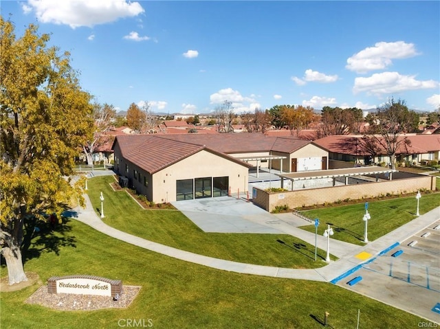 rear view of property featuring a yard, fence, and stucco siding