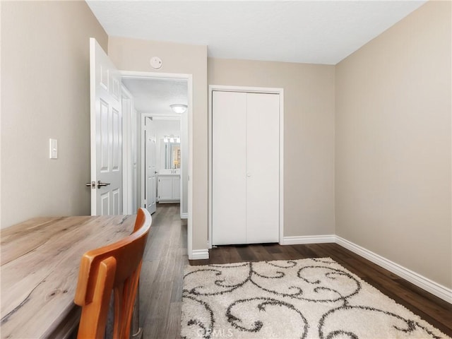 bedroom with a closet, baseboards, and dark wood-type flooring