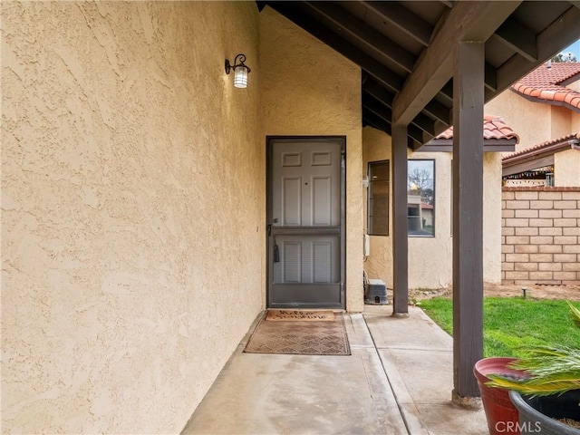 view of exterior entry featuring a tiled roof and stucco siding