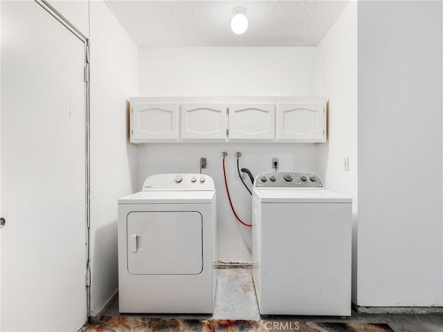 laundry area featuring a textured ceiling, separate washer and dryer, and cabinet space