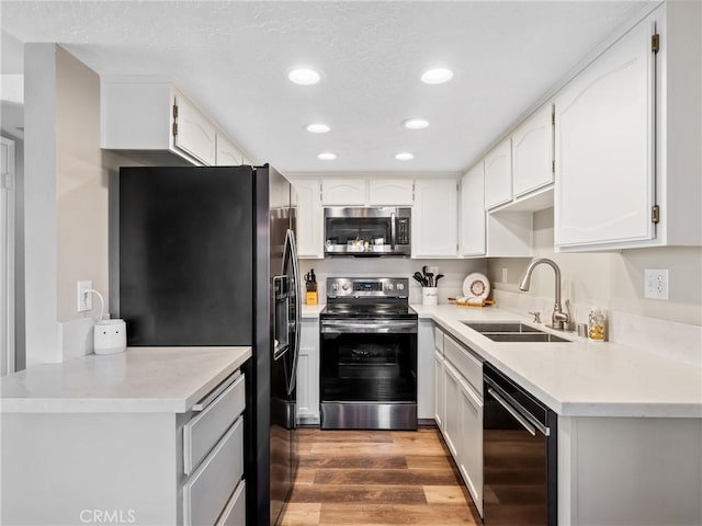 kitchen with light wood-style flooring, recessed lighting, stainless steel appliances, a sink, and white cabinets