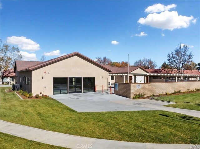 back of house with fence, a lawn, and stucco siding