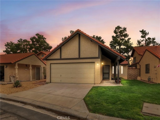 view of front facade with a garage, concrete driveway, stucco siding, a tile roof, and a front yard