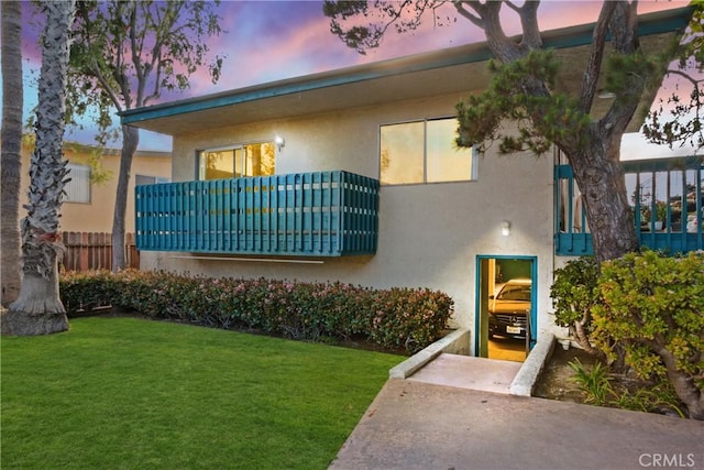 view of front of house featuring a yard, fence, and stucco siding