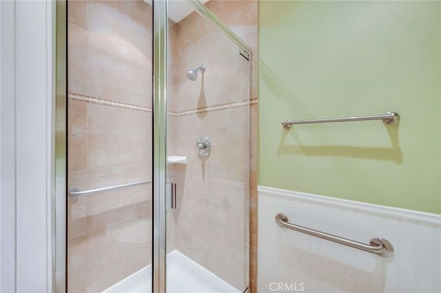 full bath featuring a shower stall and wainscoting