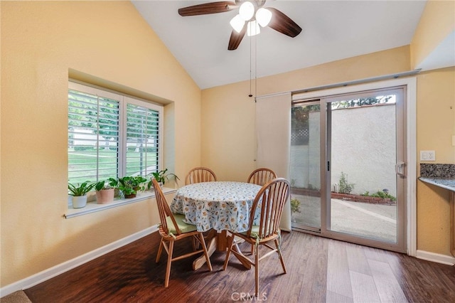 dining space featuring vaulted ceiling, wood finished floors, a ceiling fan, and baseboards