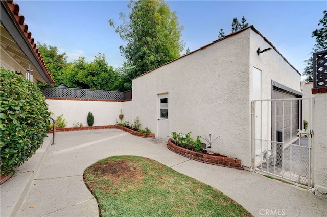 exterior space featuring a patio area, fence, and stucco siding