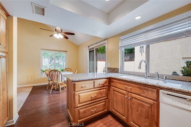 kitchen featuring visible vents, lofted ceiling, light stone countertops, white dishwasher, and a sink