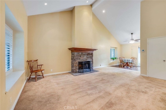 unfurnished living room featuring carpet, ceiling fan, a stone fireplace, high vaulted ceiling, and baseboards